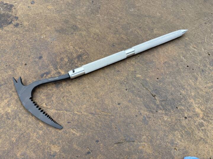 A student-built hand tool with a knurled aluminum handle and a blackened steel head with cut teeth.